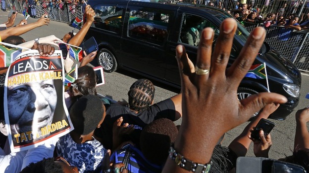 People react as the hearse carrying Nelson Mandela travels through a street in Pretoria.