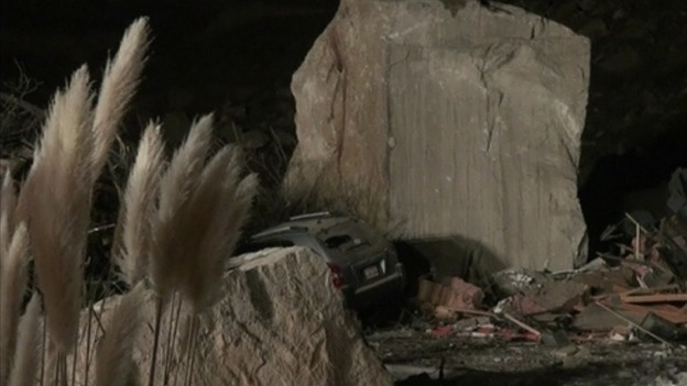 A large boulder sits on top of the a building