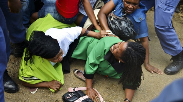Mourners fall in a stampede as they run to queue before boarding buses to take them to the Union Buildings