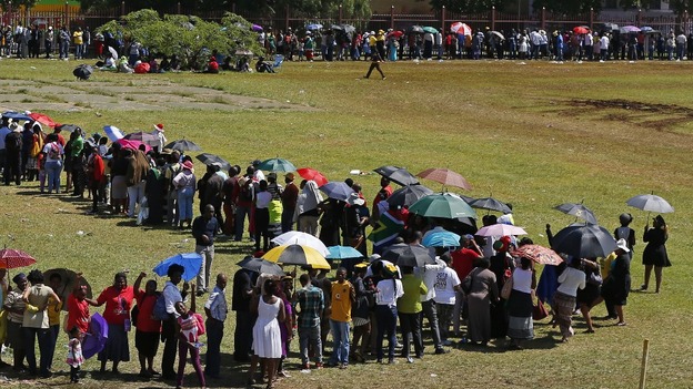 People wait in a bus line to pay their respects to Nelson Mandela.