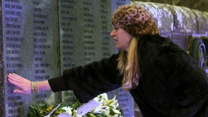 A woman touches the wall of remembrance at Dryfesdale Cemetery in Lockerbie