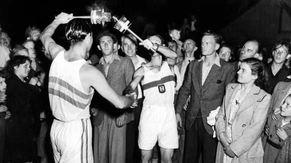 The Olympic flame is passed between runners in the village of Molash, for the next stage of its journey to Wembley
