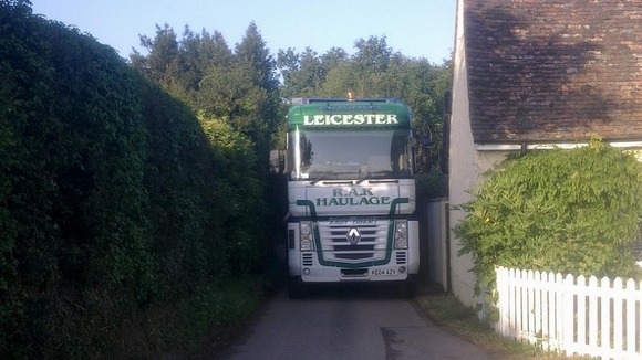 A lorry struggles to get through a village road