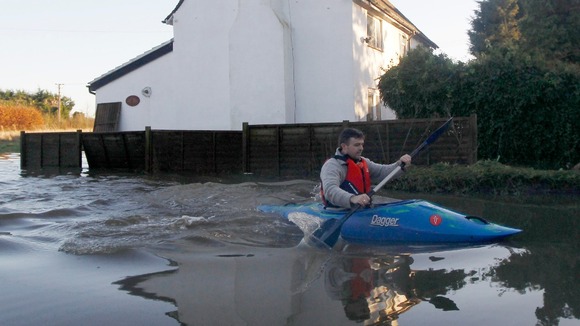A man paddles his canoe past a flooded property in Yalding on Boxing Day