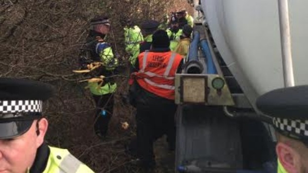 A picture of a protester near a tanker, surrounded by police