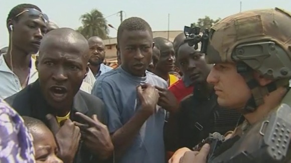 A Muslim man argues with French troops.