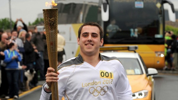 Torchbearer 001 Jordan Anderton carrying the Olympic flame on day 2