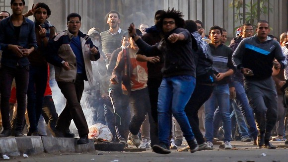 Anti-government protesters and members of the Muslim Brotherhood throw stones near Tahrir Square in clashes with army supporters