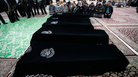 Mourners pray near the coffins of victims killed by a bomb attack at a Shi'ite Muslim village near the Iraqi city of Baquba