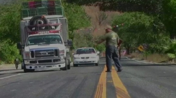 Armed men stop cars on a road in Mexico.