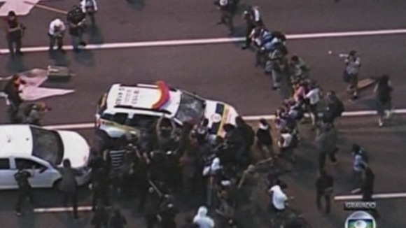 Protesters attack a police car.
