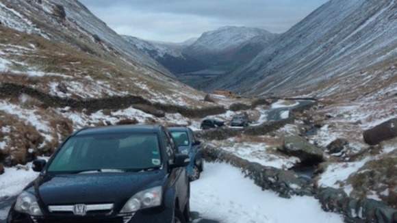 Cars abandoned overnight on a snow-covered pass in the Lake District.