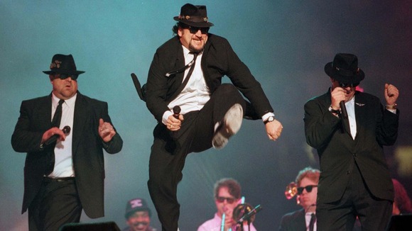 John Belushi jumps as the Blues Brothers perform at the half time show at Super Bowl in 1996.