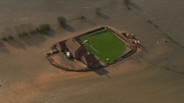 A house in Somerset is seen with high flood defences around the garden.