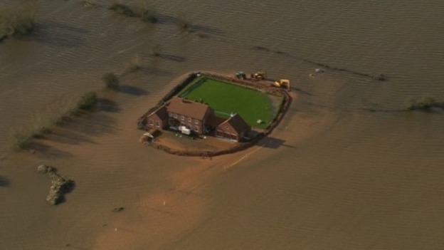 The house is surrounded by flooded fields.