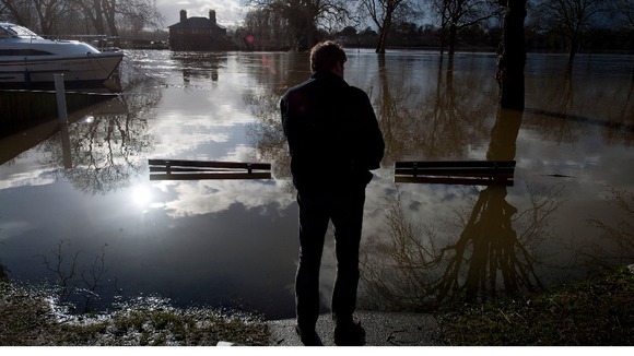 A resident looks out across the river Thames that has flooded Datchet in Berkshire