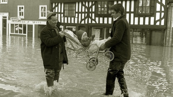 Caroline Abell, a seventeen month old baby is carried through the swirling flood waters at Frankwell, Shrewsbury, Shropshire.