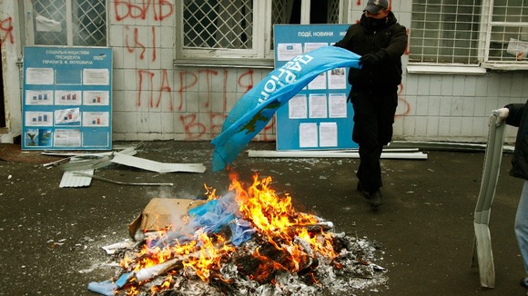 An anti-Yanukovich protester burns flags of the Party of Regions in Kiev.