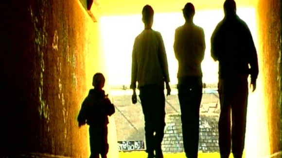 Three teenagers walk with a toddler.