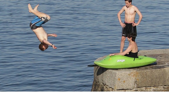 Young men jump into the water off a sea wall at Bray, Co. Dublin as the warm weather continues across Ireland