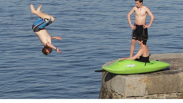 Young men jump into the water off a sea wall at Bray, Co. Dublin as the warm weather continues across Ireland
