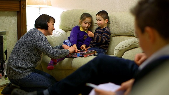 Woman plays with 2 children on the sofa