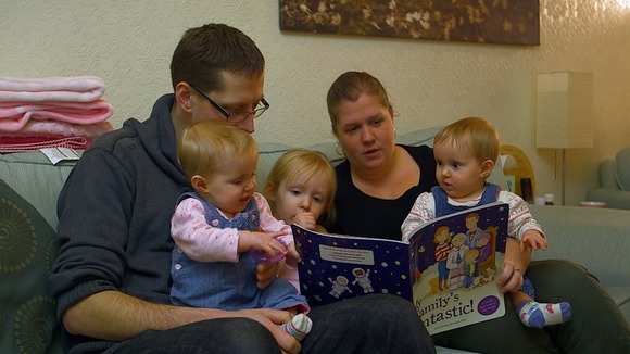 Family reading a book on the sofa