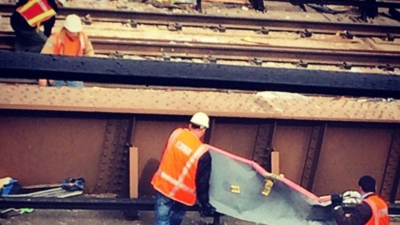 Two men lift metal from a rail track after the explosion.
