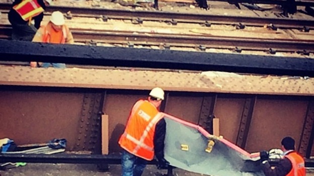 Two men lift metal from a rail track after the explosion.