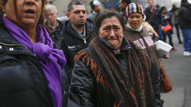 A woman cries as she is brought to the site of a building collapse in Harlem