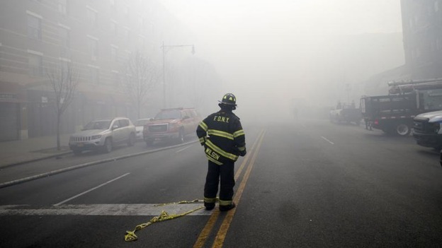 A firefighter stands in smoke filled East 116th street