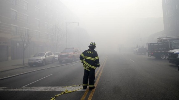 A firefighter stands in smoke filled East 116th street
