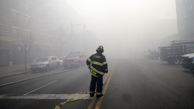 A firefighter stands in smoke filled East 116th street