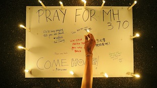 A woman places a lighted candle on a poster during a candlelight vigil near Kuala Lumpur.