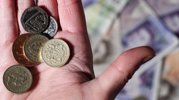 File photo of coins in a person's hands with notes in the background.
