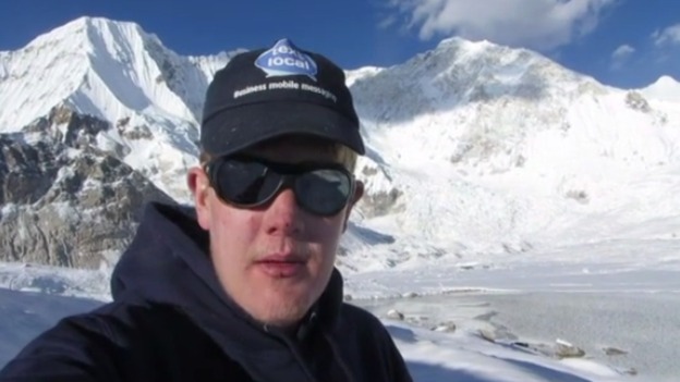 Alex Staniforth wearing a hat and glasses in the snowy mountains