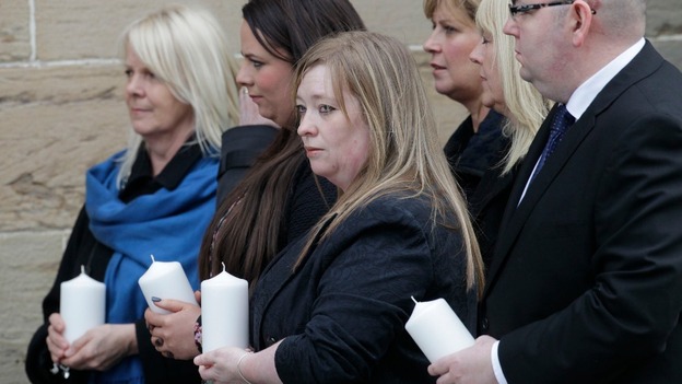 Members of the congregation hold candles outside the memorial service.
