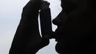 File photo of a woman taking a puff on an inhaler.