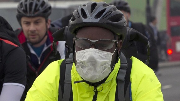 A cyclist wears a mask as he crosses London bridge in the smog this morning.