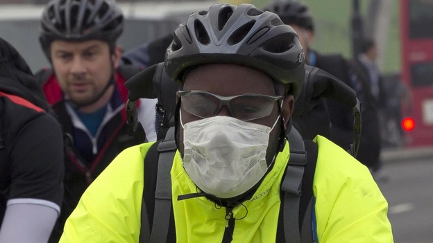 A cyclist wears a mask as he crosses London bridge in the smog this morning.