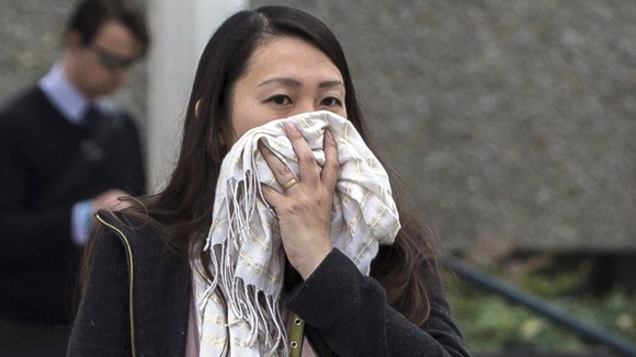 A woman covers her face as she pushes her baby in the smog.