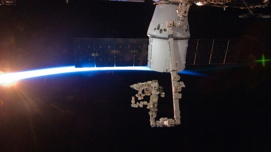 Rays of sunshine and Earth's thin blue atmosphere behind the SpaceX Dragon commercial cargo craft