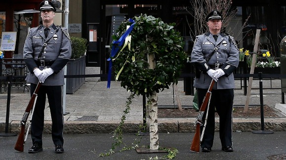 Honour guards stand beside a wreath at the site of one of the two bomb blasts that took place during last year's Boston Marathon.