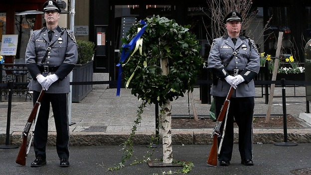 Honour guards stand beside a wreath at the site of one of the two bomb blasts that took place during last year's Boston Marathon.