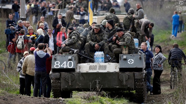 Ukrainian soldiers sit on top of armoured personnel carriers surrounded by pro-Russian separatists.