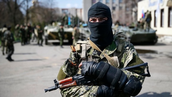 An armed man stands guard with armoured personnel carriers in the background in Slaviansk, eastern Ukraine.