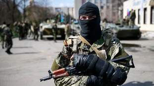 An armed man stands guard with armoured personnel carriers in the background in Slaviansk, eastern Ukraine.