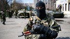 An armed man stands guard with armoured personnel carriers in the background in Slaviansk, eastern Ukraine.