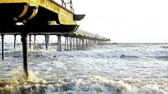 tide crashing against pier and beach at Saltburn