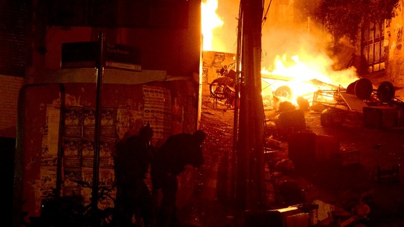 Policemen take up position next to barricades on fire.